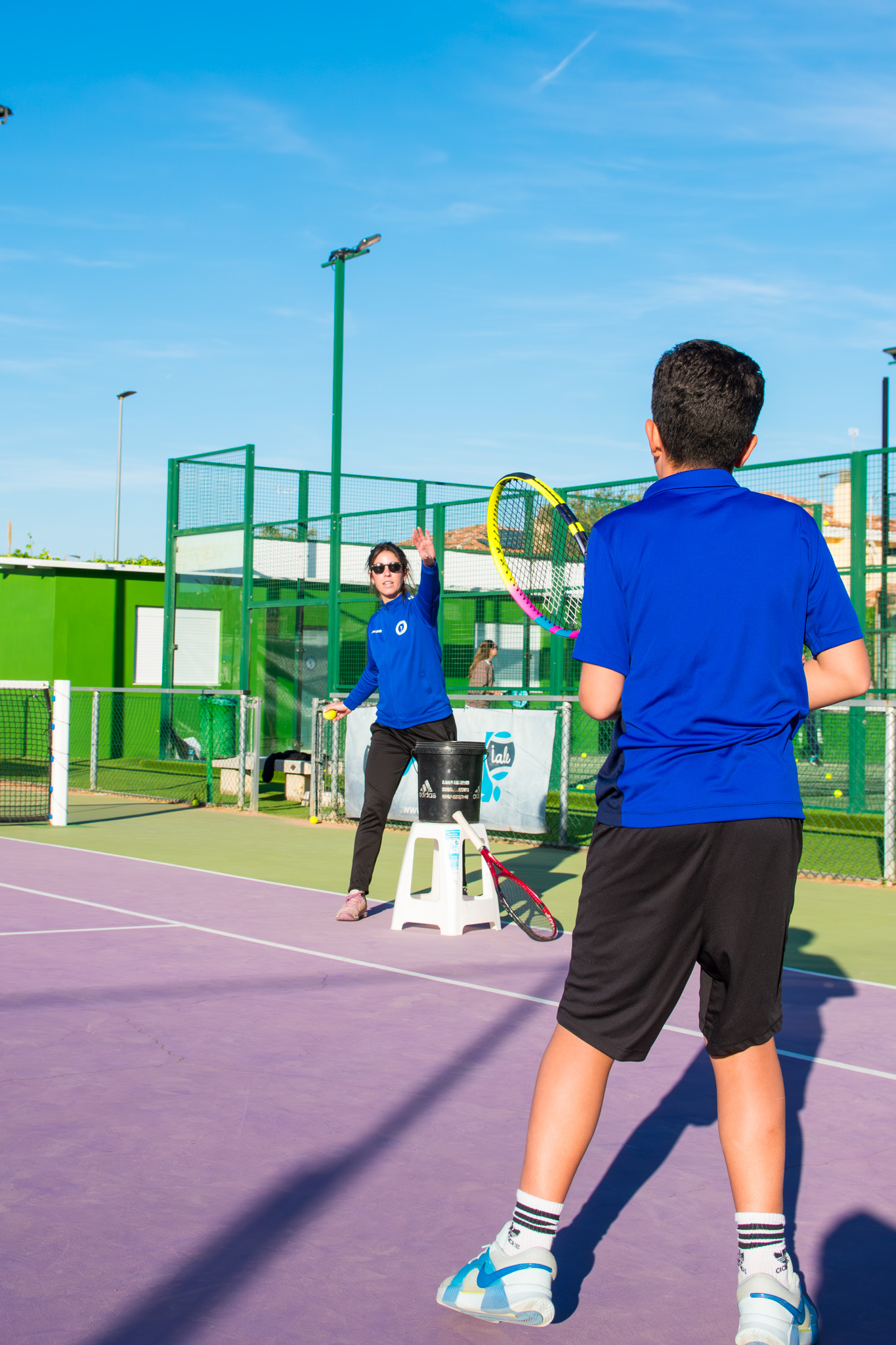 Entrenadora de tenis y alumno en clase de tenis de iniciación.