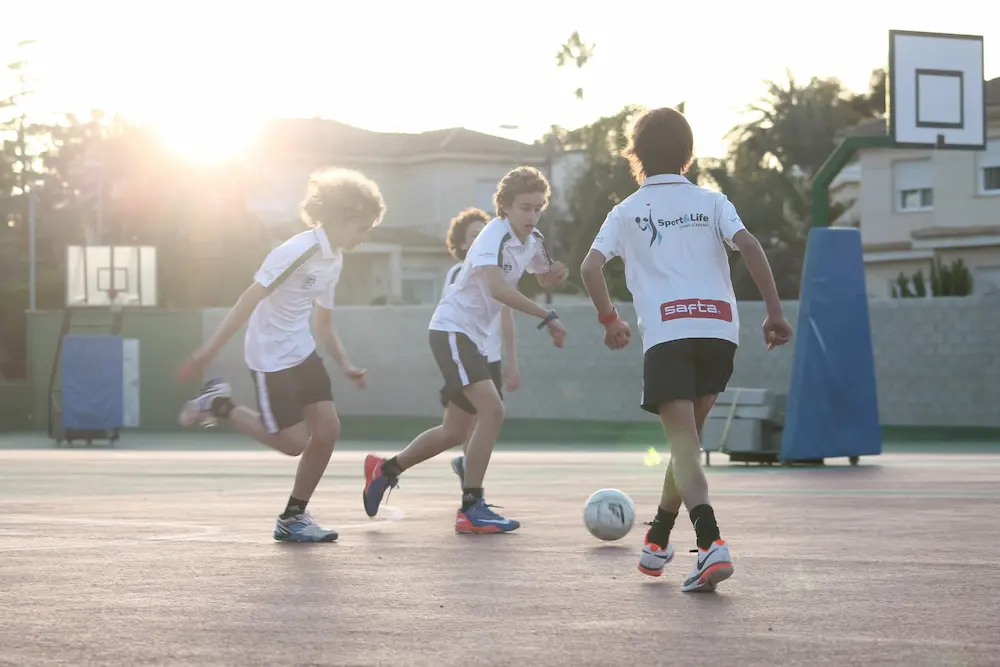 Niños jugando a fútbol en el campus de verano.
