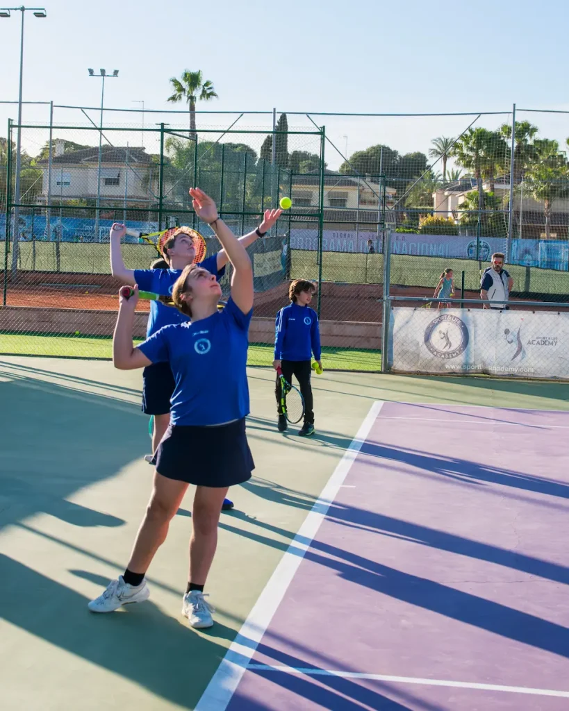 Grupo practicando saque de tenis.