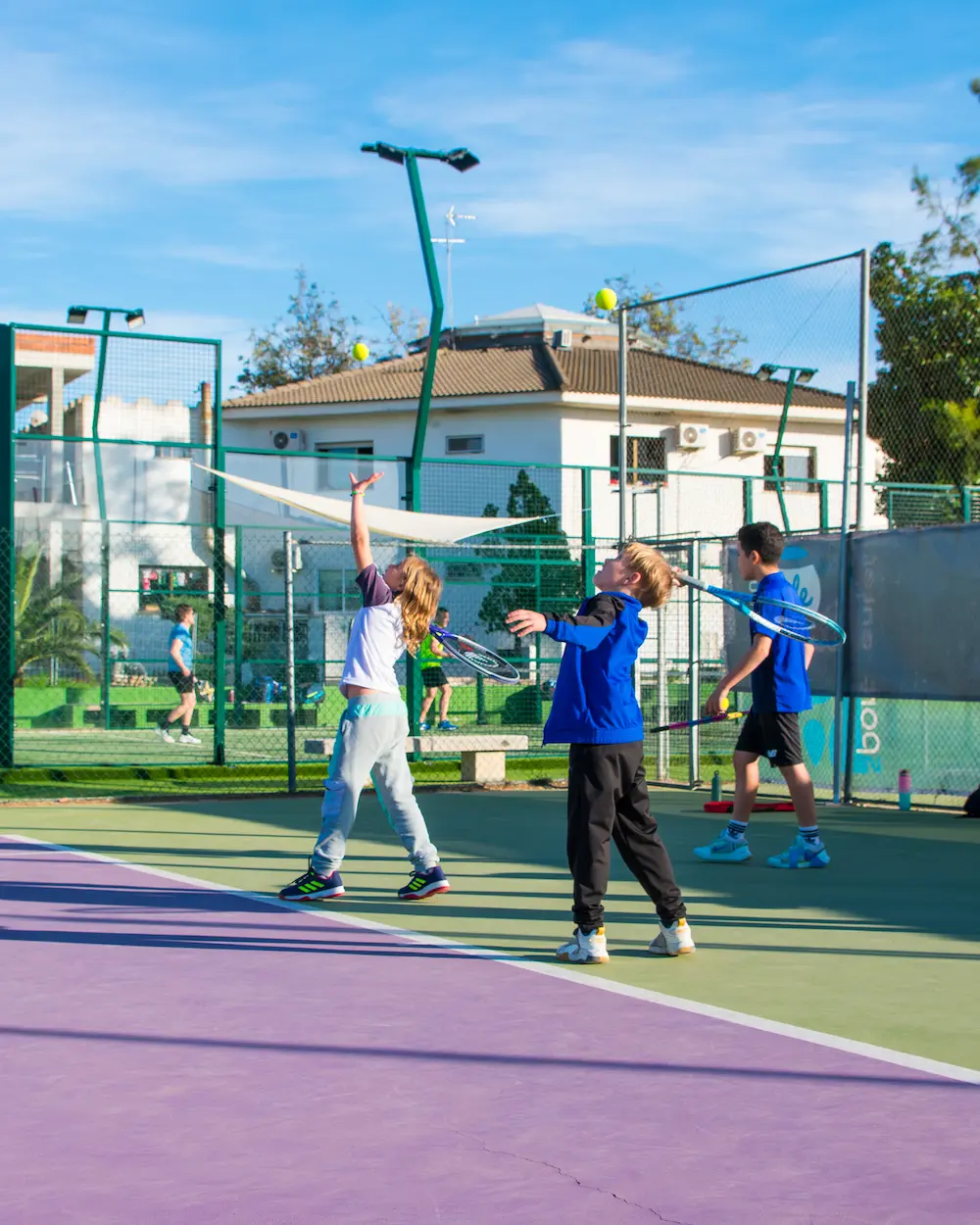 Sesión de entrenamiento de tenis con niños, aprendiendo saque.